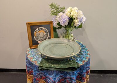 Table display with a ceramic bowl, flowers, and framed artwork