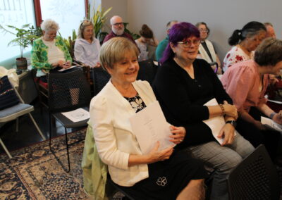 Two congregation members seated, smiling, holding programs