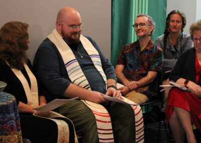 Clergy in a prayer shawl seated among the congregation