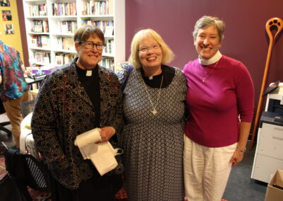 Three clergywomen posing together, smiling